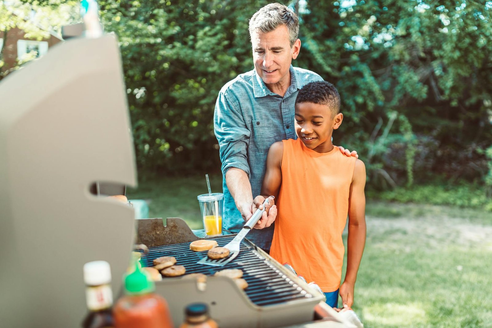 a father teaching his son how to cook hamburgers